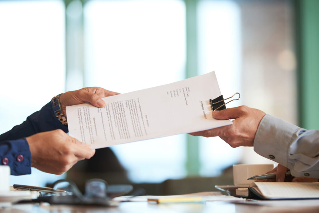 Professionals exchanging a document to represent a certificate of destruction and documented proof of secure data destruction services.