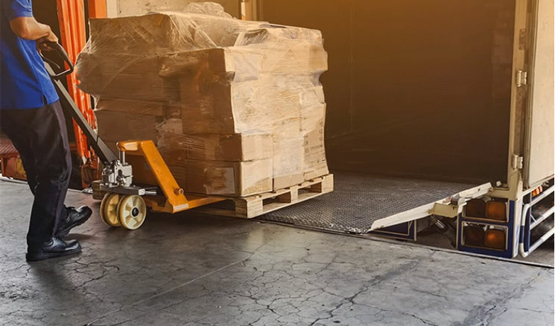 Worker moving a wrapped pallet into a truck, representing secure logistics and chain-of-custody support for media destruction services.