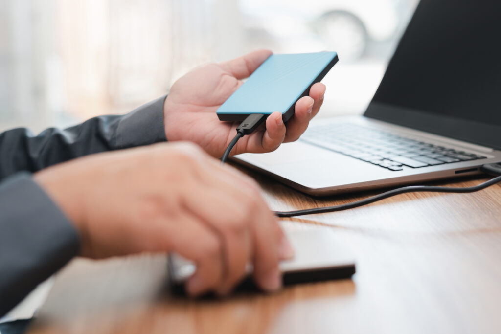 Person connecting a portable external hard drive to a laptop.