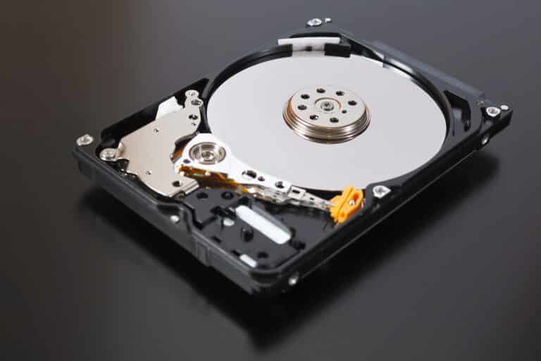 A disassembled open hard disk drive HDD of a computer or laptop lies on a dark matte surface.