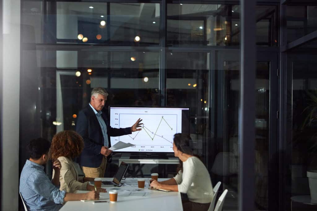 Team reviews performance metrics in a conference room, representing business decision-making around commercial electronics recycling versus disposal