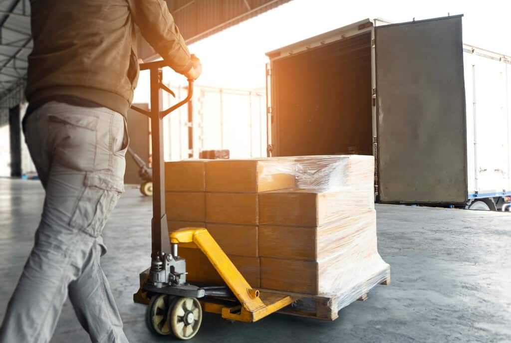 Worker moves palletized electronics at a loading dock for commercial electronics recycling pickup and transport