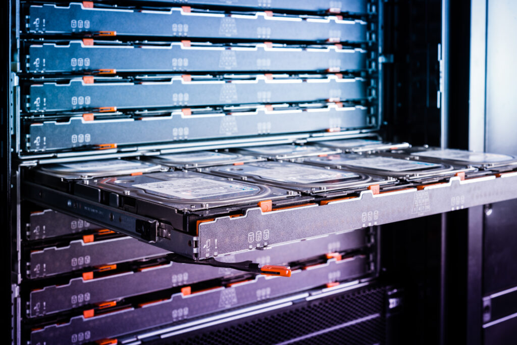 Pulled-out enterprise storage tray with multiple hard drives inside a high-density server rack, illustrating enterprise storage management in a data center.
