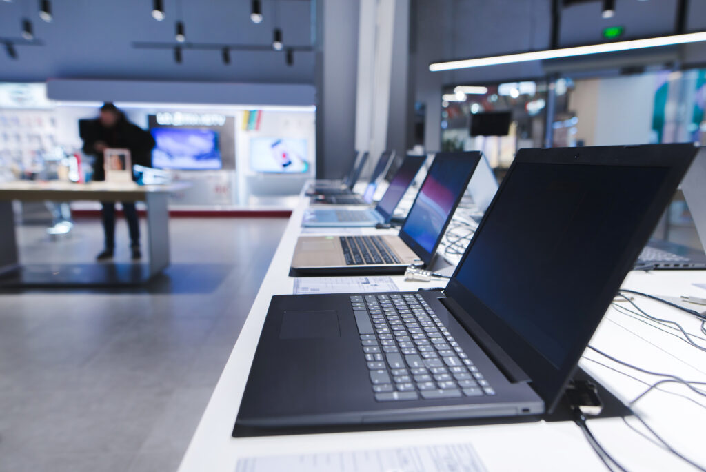 Row of laptops on display in an electronics store.