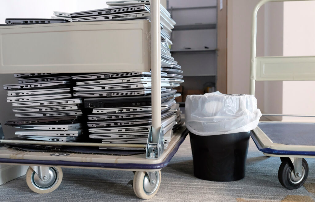Cart loaded with retired laptops collected for office electronics recycling.