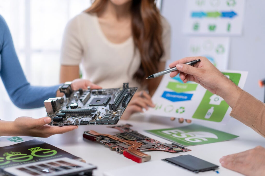 A team points to a circuit board, and a paper that says 'ESG' is on the table below.