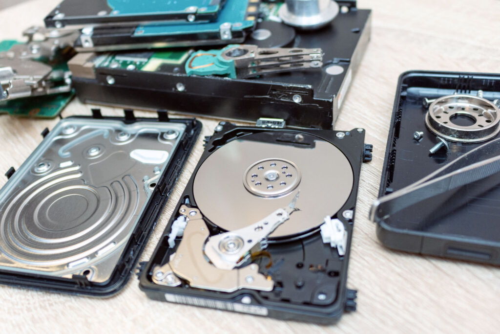 Disassembled hard drives and components on a workbench for data destruction