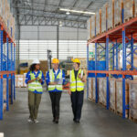 An ITAD warehouse team walks down the aisle, checking boxes