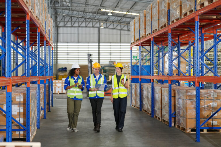 An ITAD warehouse team walks down the aisle, checking boxes