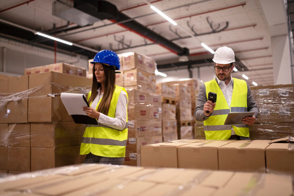 Warehouse workers scanning boxes and checking a clipboard