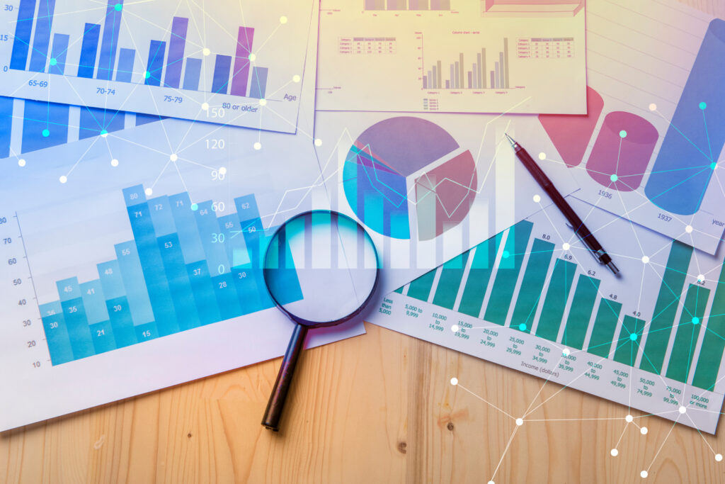 Printed charts, graphs, and a magnifying glass on a desk, representing SOC 3 reporting, audit analysis, compliance review, and data transparency.