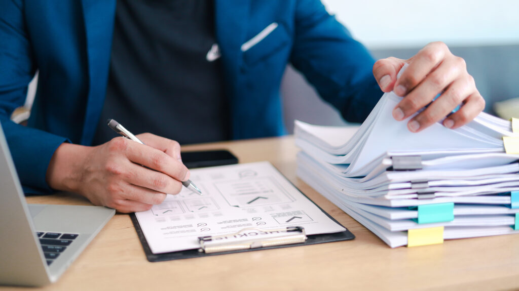 Man reviewing and writing on a compliance checklist at a desk, representing a report for those wondering: what is a SOC 3 report?
