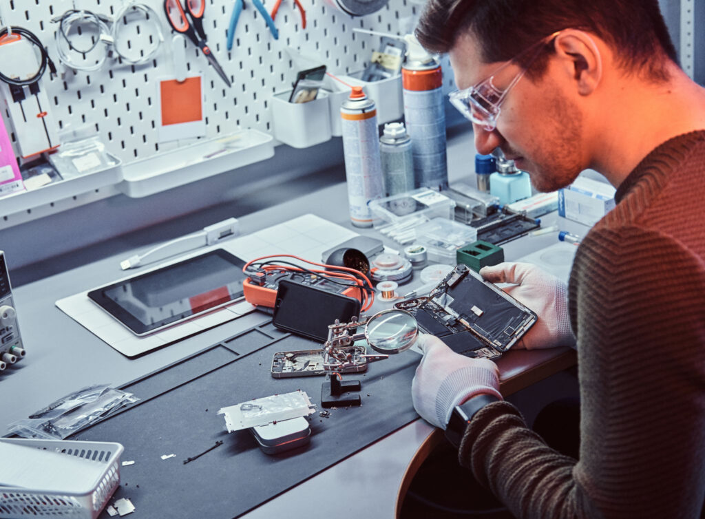 An ITAD program refurbisher dismantles a smartphone for repair.
